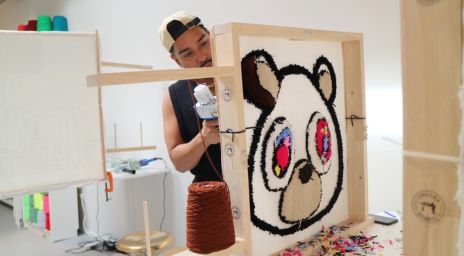 Male tufting a rug designed as a bear