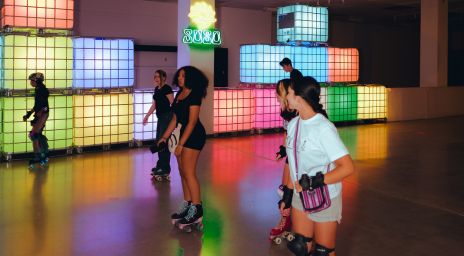 Several people roller skating at SUSO Skate Co. with lights in the back.