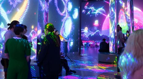 People interacting at a party with digital projections and cosmic-themed visuals