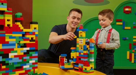 Father and son playing with colourful LEGO bricks at Legoland.