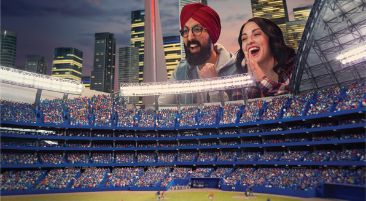 People watching a miniature Blue Jays game through the open roof of a model Rogers Centre